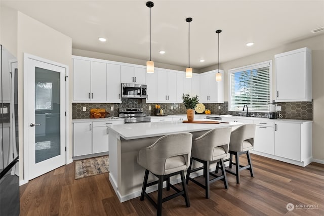 kitchen featuring stainless steel appliances, dark hardwood / wood-style flooring, and white cabinets