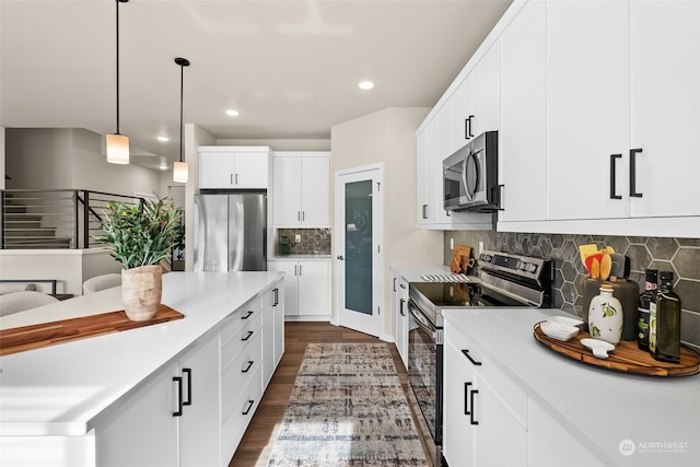 kitchen featuring backsplash, appliances with stainless steel finishes, decorative light fixtures, and white cabinets