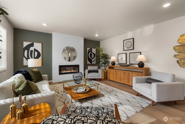 living room featuring a large fireplace, light hardwood / wood-style flooring, and a wealth of natural light