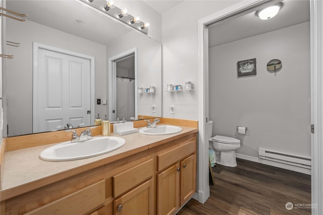 bathroom featuring wood-type flooring, a baseboard heating unit, vanity, and toilet