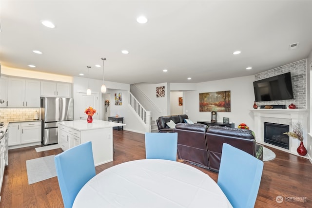 dining space with a large fireplace and dark hardwood / wood-style flooring