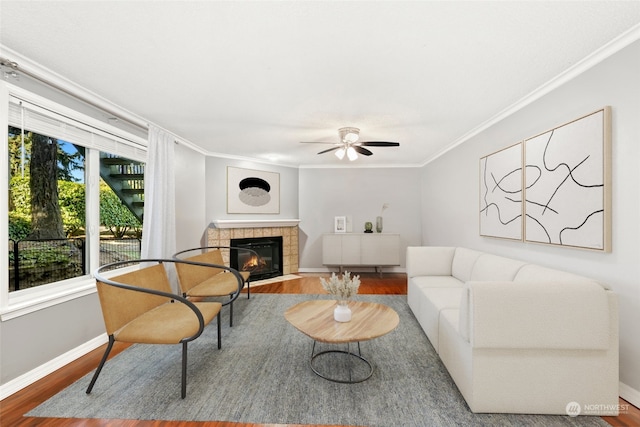 living room featuring a fireplace, ornamental molding, hardwood / wood-style flooring, and ceiling fan