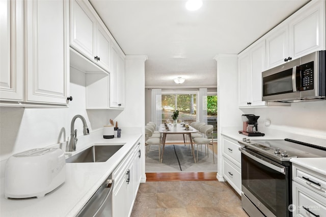 kitchen with stainless steel appliances, white cabinets, sink, and light wood-type flooring