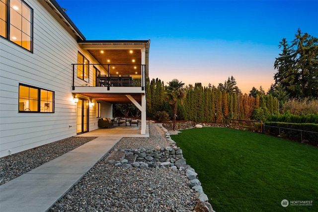 yard at dusk with a balcony and a patio