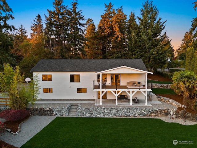 back house at dusk with a patio and a yard