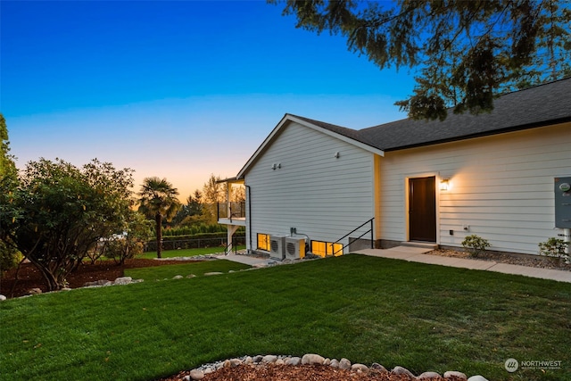 back house at dusk featuring a lawn