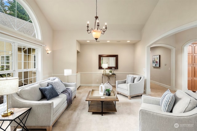 carpeted living room with an inviting chandelier and high vaulted ceiling