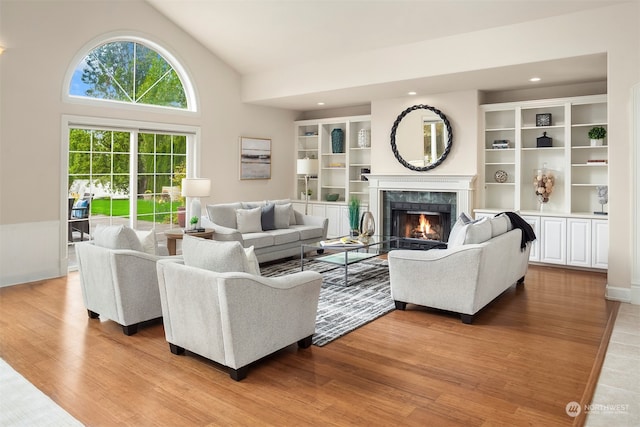 living room with light hardwood / wood-style floors, a fireplace, and high vaulted ceiling