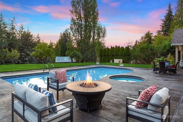 pool at dusk featuring a lawn, an in ground hot tub, a patio area, and an outdoor living space with a fire pit