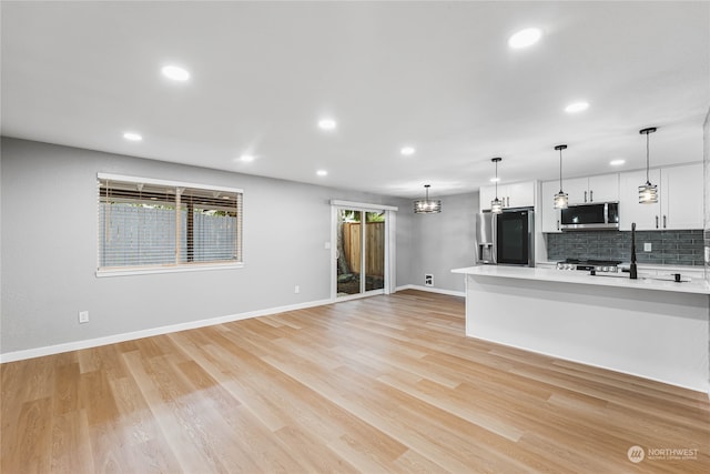 unfurnished living room featuring a chandelier and light hardwood / wood-style flooring