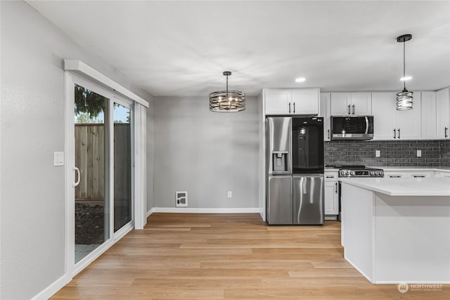 kitchen with light wood-type flooring, decorative backsplash, white cabinets, appliances with stainless steel finishes, and decorative light fixtures