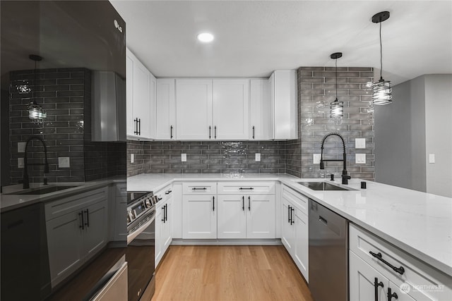 kitchen featuring light hardwood / wood-style flooring, sink, hanging light fixtures, white cabinets, and appliances with stainless steel finishes