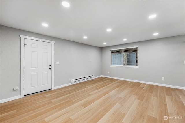 empty room with baseboard heating and light hardwood / wood-style flooring