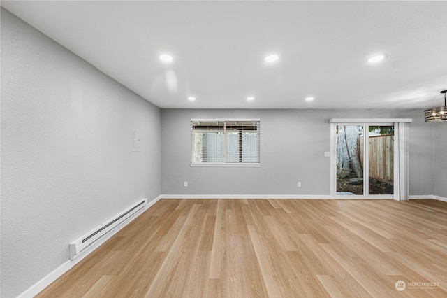 unfurnished room featuring a baseboard radiator, an inviting chandelier, and light hardwood / wood-style flooring