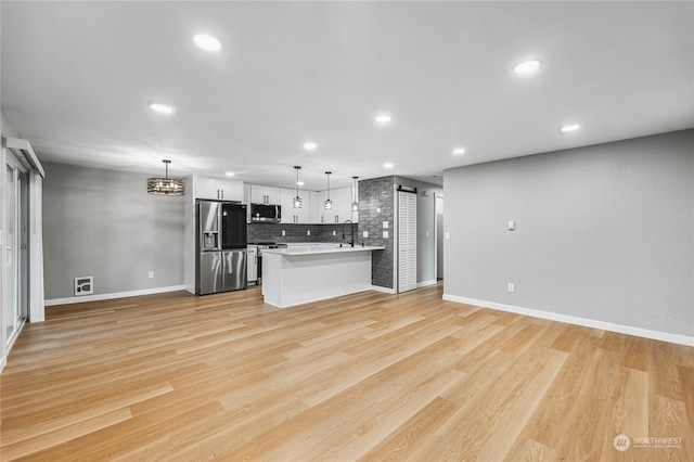 unfurnished living room featuring an inviting chandelier and light hardwood / wood-style flooring