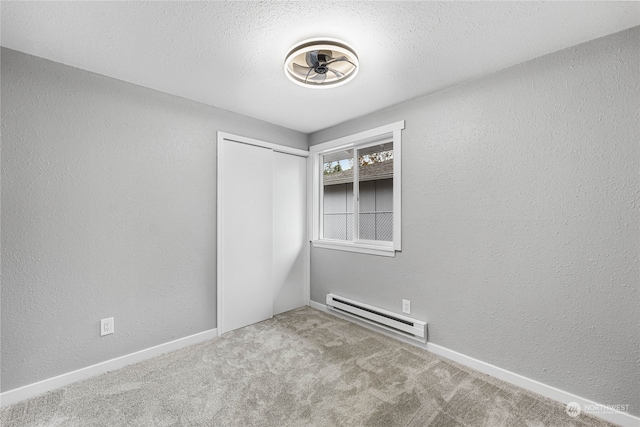 carpeted empty room with a textured ceiling and baseboard heating