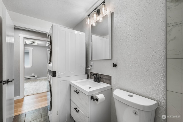 bathroom with vanity, wood-type flooring, a textured ceiling, baseboard heating, and toilet