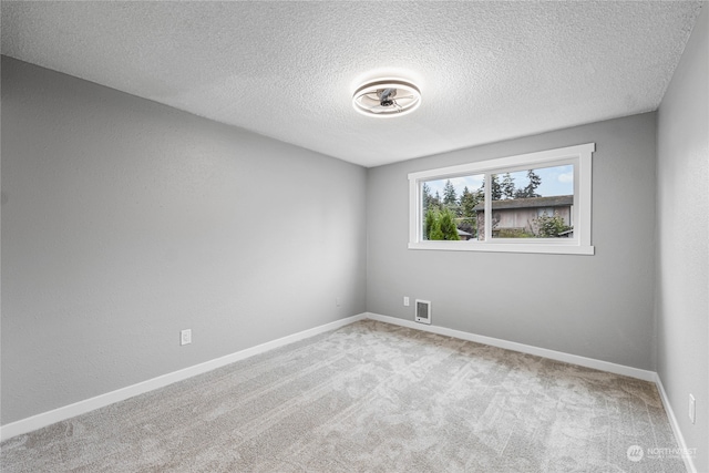 empty room featuring a textured ceiling and light carpet