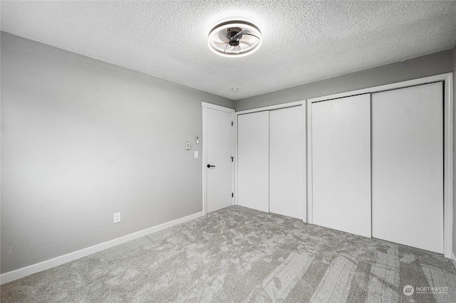 unfurnished bedroom featuring a textured ceiling, two closets, and carpet flooring