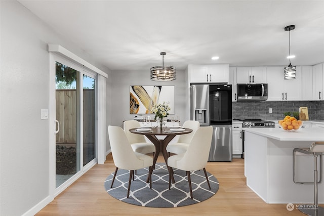 kitchen with appliances with stainless steel finishes, light wood-type flooring, decorative light fixtures, and white cabinets