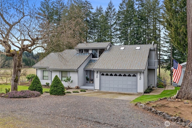 view of front facade with gravel driveway, a tile roof, and an attached garage