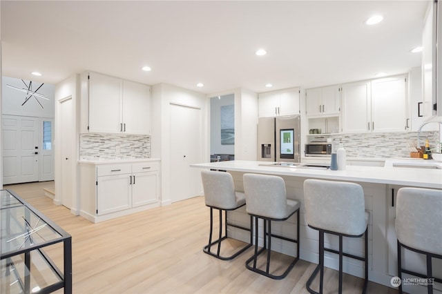 kitchen featuring sink, white cabinets, stainless steel appliances, and light wood-type flooring