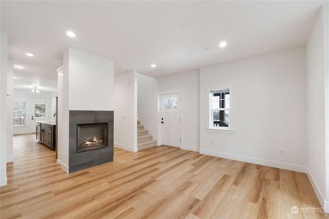 unfurnished living room with a tile fireplace and light hardwood / wood-style flooring