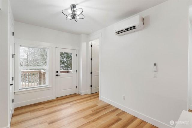 doorway with a notable chandelier, a wall unit AC, and light wood-type flooring