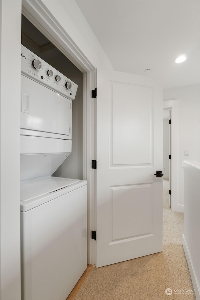 clothes washing area with light carpet and stacked washer / dryer