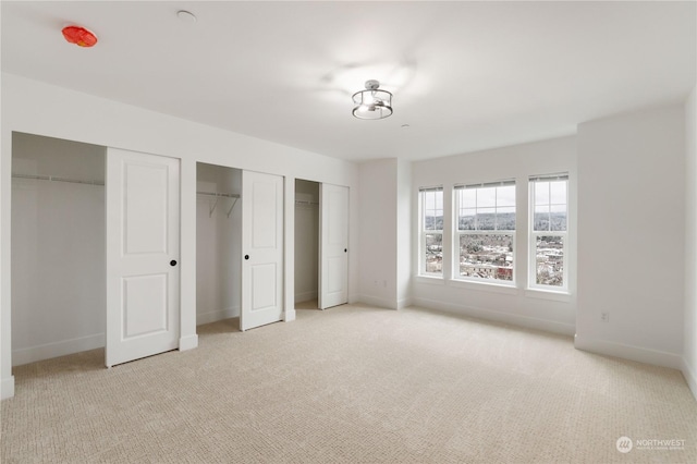 unfurnished bedroom with light carpet and two closets