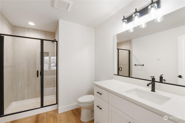 bathroom featuring vanity, hardwood / wood-style floors, a shower with shower door, and toilet