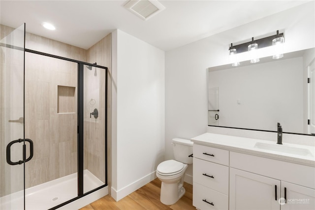 bathroom featuring vanity, toilet, a shower with shower door, and hardwood / wood-style floors