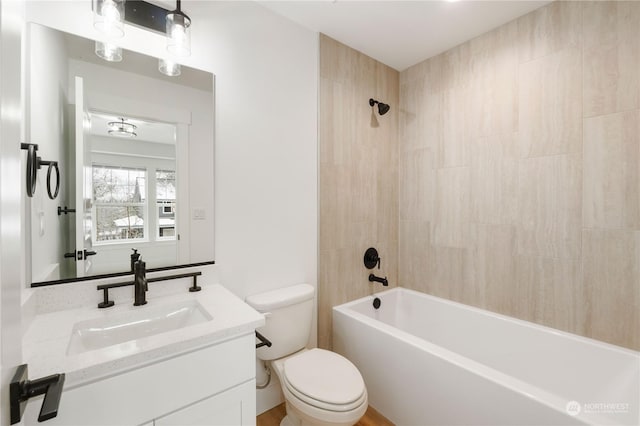 full bathroom featuring vanity, tiled shower / bath combo, and toilet