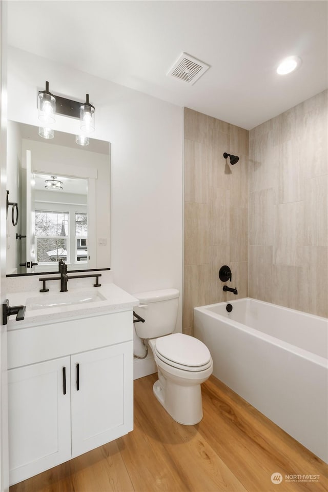 full bathroom with hardwood / wood-style flooring, vanity, toilet, and tiled shower / bath