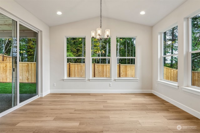 unfurnished sunroom with a healthy amount of sunlight, vaulted ceiling, and an inviting chandelier