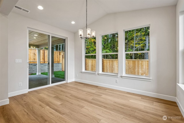 unfurnished dining area featuring a chandelier, light wood-type flooring, and vaulted ceiling