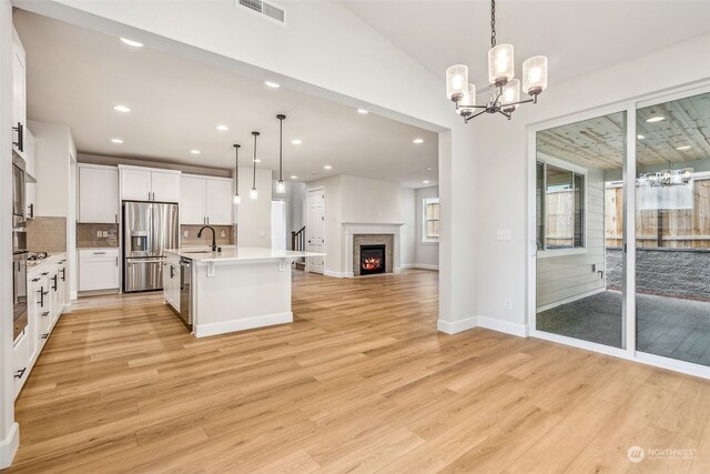 kitchen featuring decorative backsplash, appliances with stainless steel finishes, decorative light fixtures, and light wood-type flooring