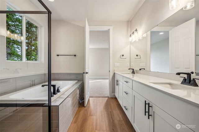 bathroom featuring vanity, wood-type flooring, and tiled tub