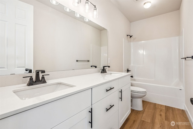 full bathroom with toilet, hardwood / wood-style floors, vanity, and  shower combination