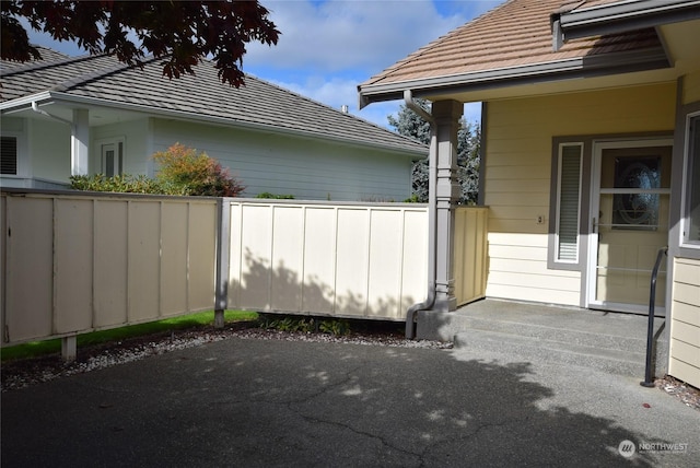 view of side of property with a tile roof and fence