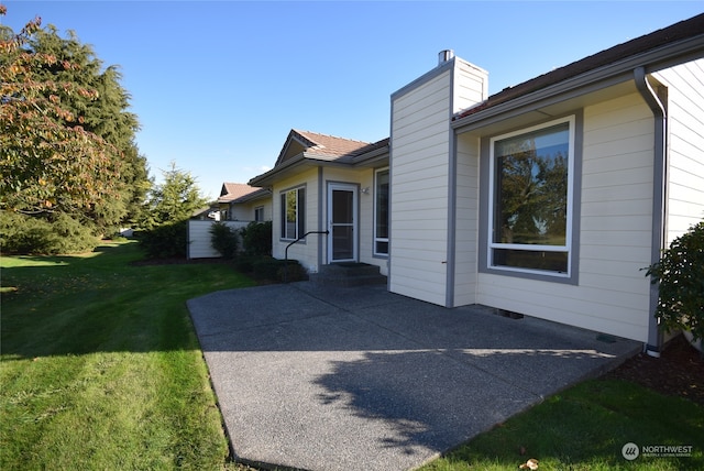 view of property exterior with a patio area and a lawn