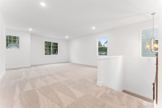 carpeted spare room featuring a chandelier