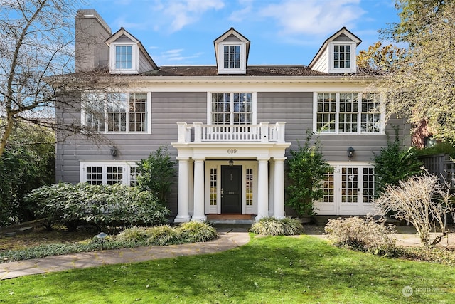 colonial-style house with a front yard, french doors, and a balcony