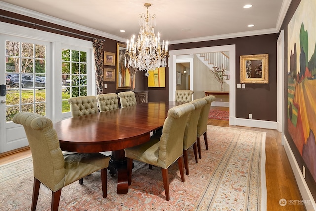 dining area featuring wood-type flooring, ornamental molding, and a notable chandelier