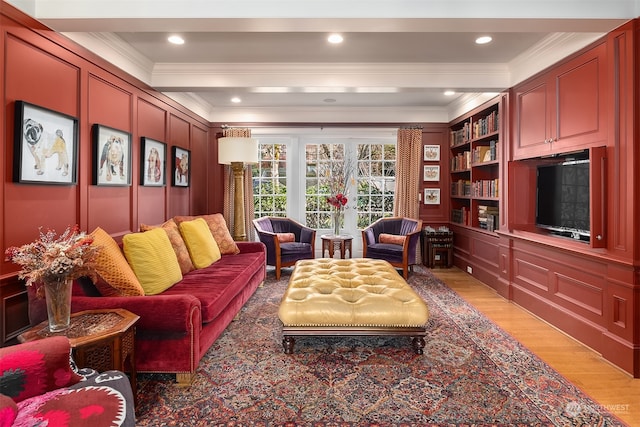 living room featuring wood-type flooring, ornamental molding, beamed ceiling, and built in features