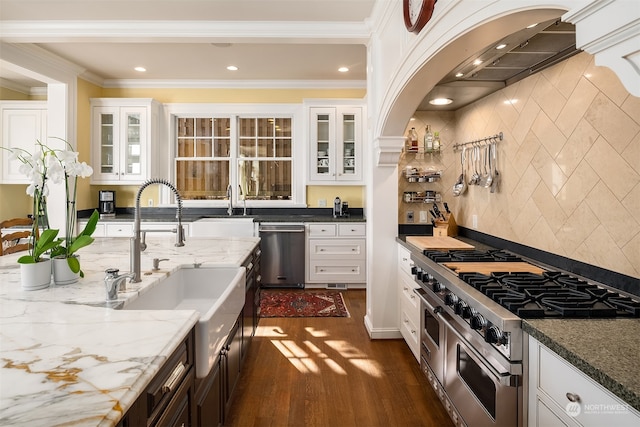 kitchen with appliances with stainless steel finishes, light stone countertops, ornamental molding, and dark hardwood / wood-style flooring