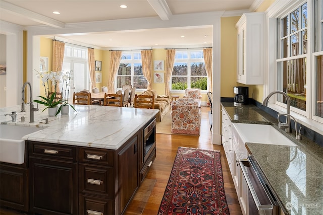 kitchen featuring beamed ceiling, stainless steel appliances, sink, white cabinetry, and dark brown cabinets