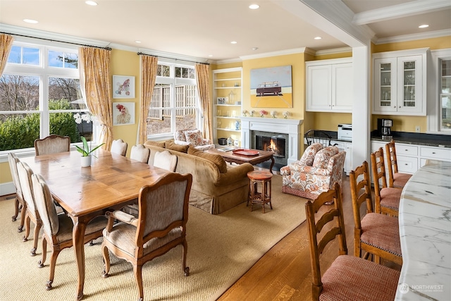 dining area with light wood-type flooring, beam ceiling, and ornamental molding