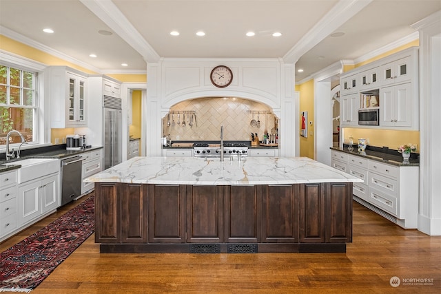 kitchen featuring an island with sink, light stone counters, and stainless steel appliances