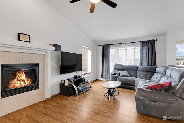 living room featuring hardwood / wood-style flooring, a fireplace, ceiling fan, and high vaulted ceiling